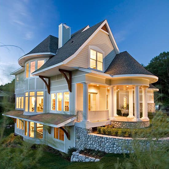 House plan exterior featuring a rounded facade, multiple gables, and a portico with classical columns.