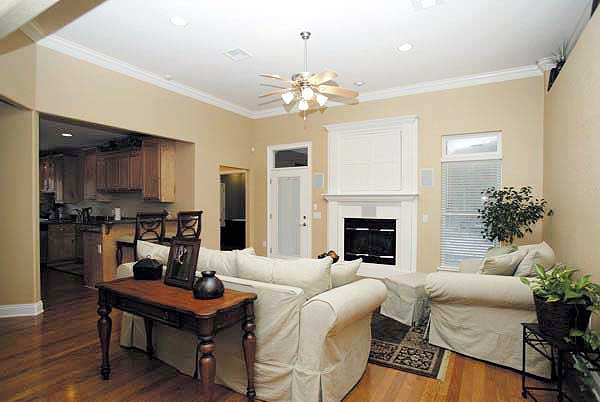 Great room interior with fireplace, view of kitchen, and neutral-toned furniture.