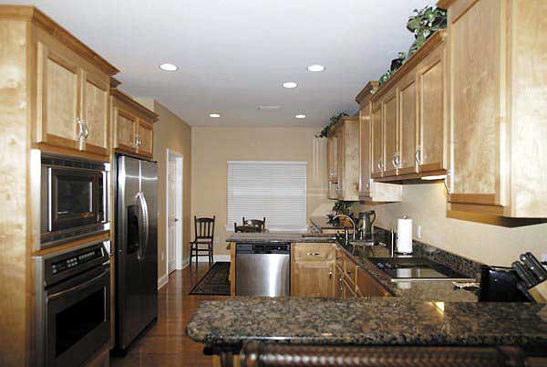 Kitchen with light wood cabinets, stainless steel appliances including a built-in oven and microwave, granite countertops, and pendant lighting.