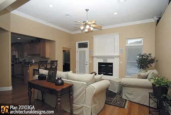 Living room with fireplace, view of kitchen, and a ceiling fan.