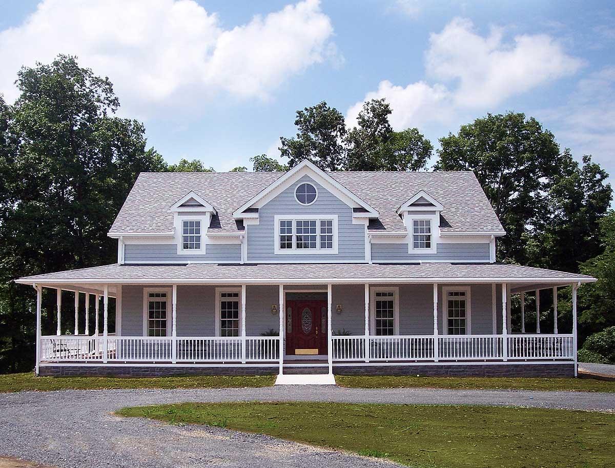 House plan exterior: Two-story home with wrap-around porch, dormers, and central circular window.