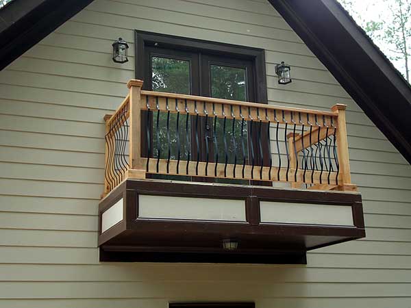 House plan exterior with a second-story balcony featuring wooden railings with black spindles and a cantilevered base.