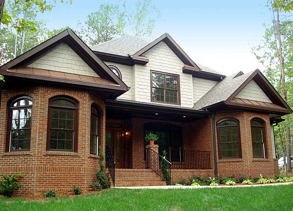 House plan exterior featuring brick lower level, shingle siding, arched windows, and multi-level gabled rooflines.