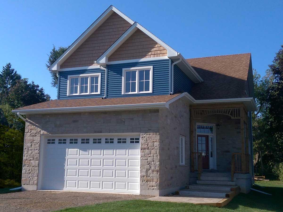 House plan exterior with two stories, stone veneer, front-facing garage, and covered porch with decorative brackets.