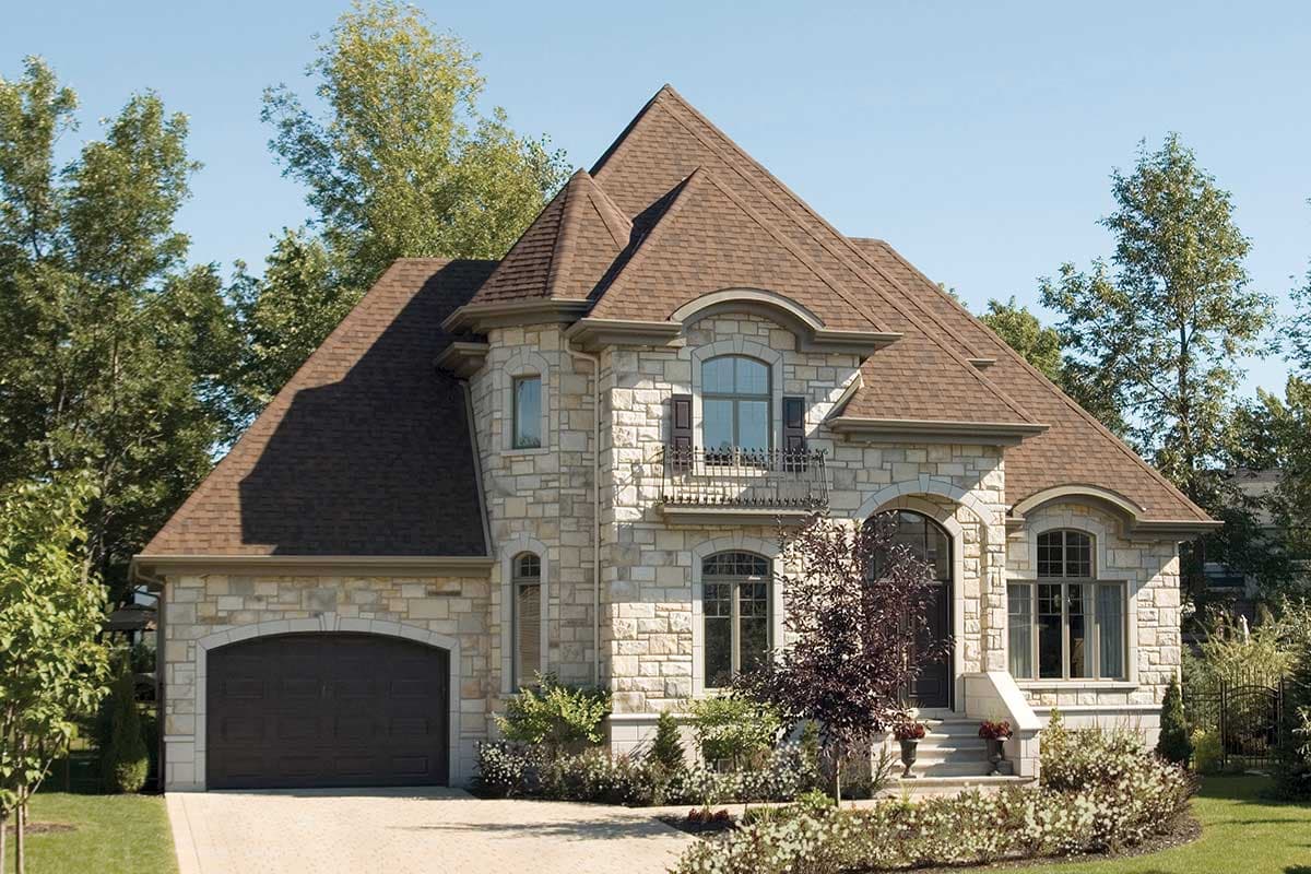 House plan exterior. Two-story home with stone facade, arched entryway, and multi-gabled roof. Includes a side-entry garage.