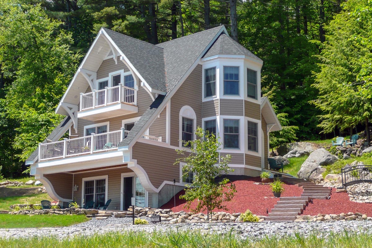 House plan exterior with multi-story construction, featuring a bay window, gabled roof, and balconies with railings.