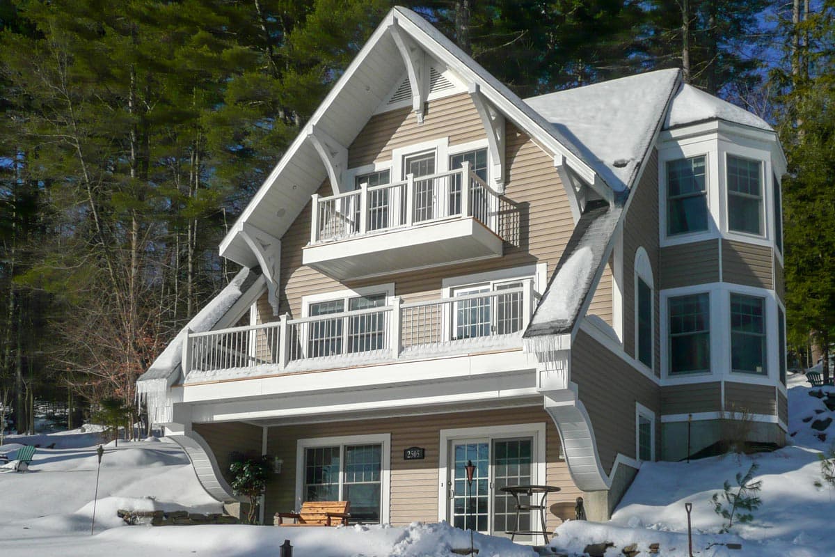 House plan exterior with prominent gables, two balconies, and a bay window section.