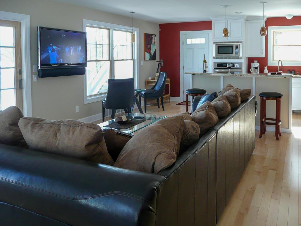 Living room and kitchen with island seating, white cabinets, microwave, and television.