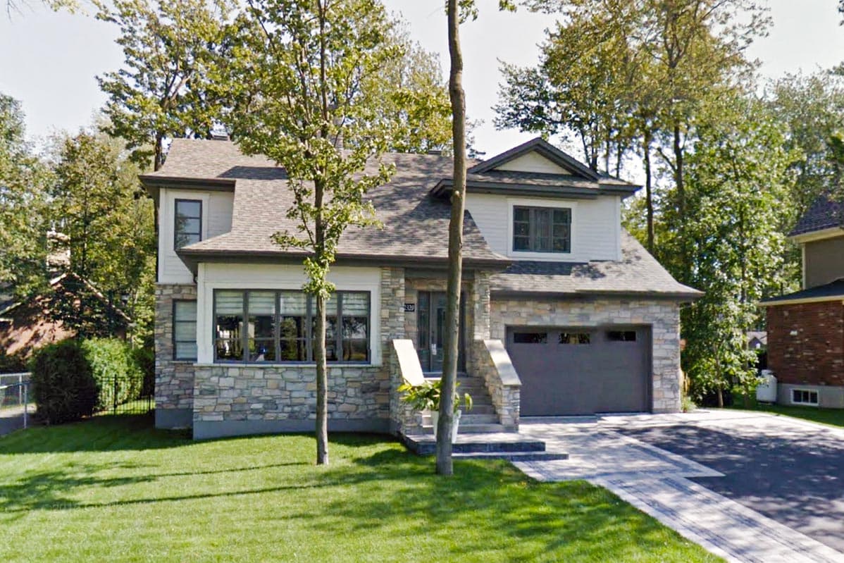 House plan exterior: Two-story home with stone and white siding, gabled dormer, and attached garage.