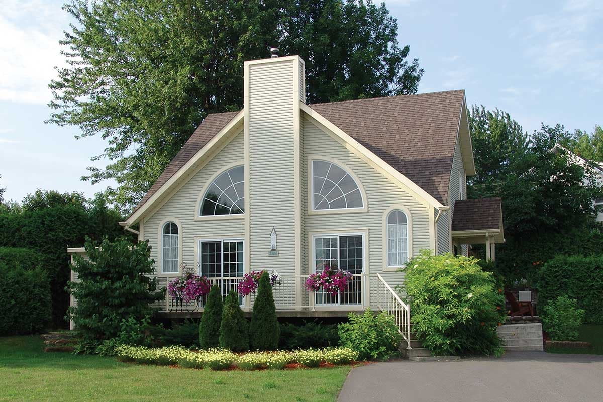 House plan exterior: Two-story home with prominent central chimney, arched windows, and covered porch.