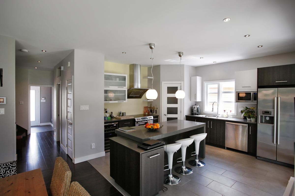 Modern kitchen with large island, stainless steel appliances, ample cabinet storage, and dark wood cabinetry.