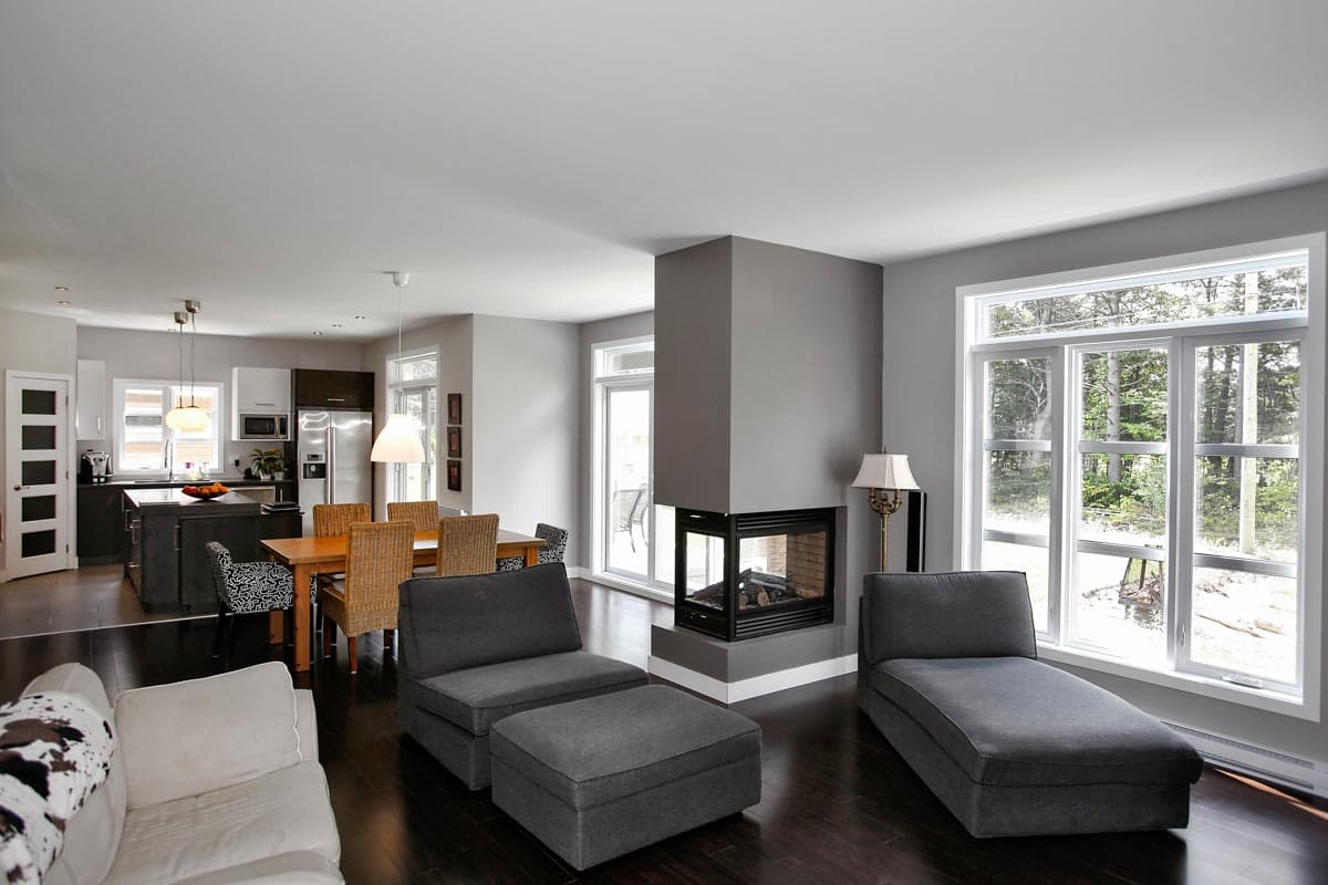 Open-concept living area with kitchen, dining table, fireplace, and large windows.