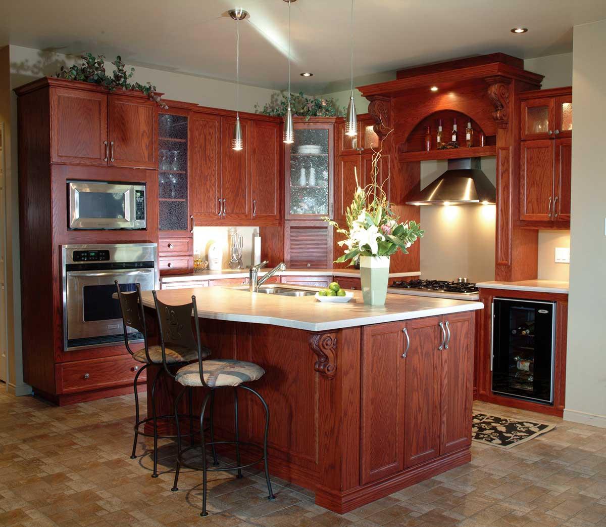 Kitchen interior featuring wood cabinetry, an island with seating, stainless steel appliances including a microwave and oven, and a range hood.