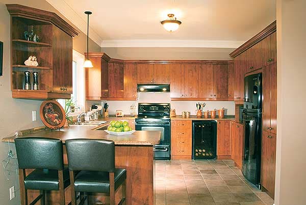 Kitchen with light wood cabinets, dark granite countertops, stainless steel appliances, and a breakfast bar with two stools.