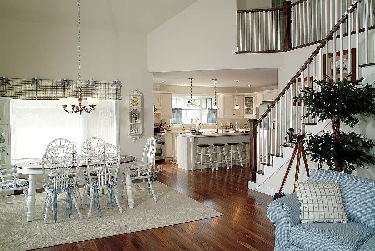 Dining area and kitchen with island, open to living space with staircase. Vaulted ceiling over dining.