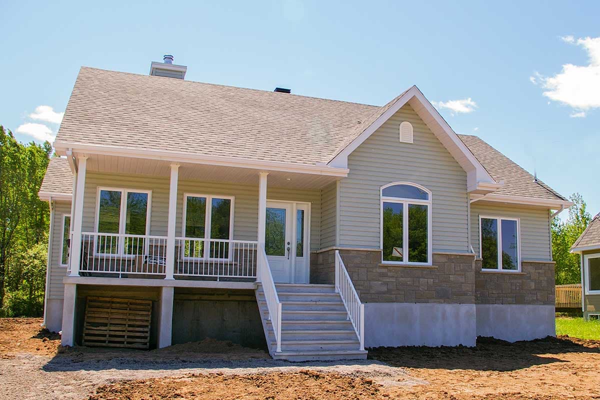 House plan exterior: Single-story home with covered porch, stone veneer wainscoting, gabled dormer, and prominent front entry stairs.
