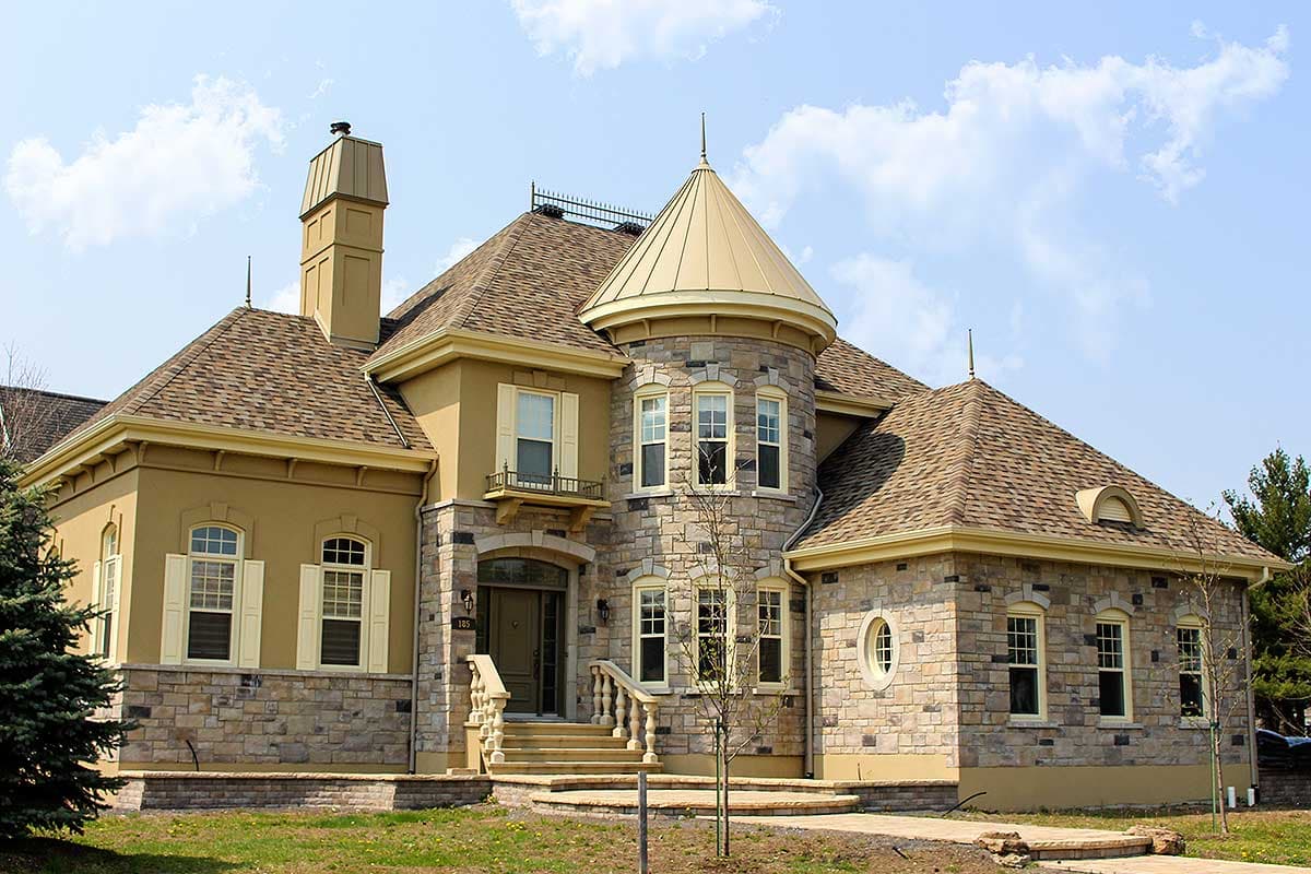 House plan exterior with stone and stucco facade, prominent turret, and multi-level roof.