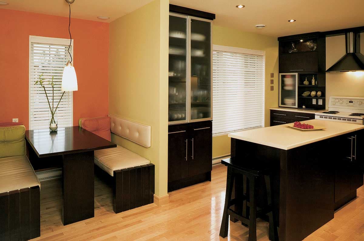 Kitchen with island, built-in banquette seating, and tall cabinet storage with glass doors.
