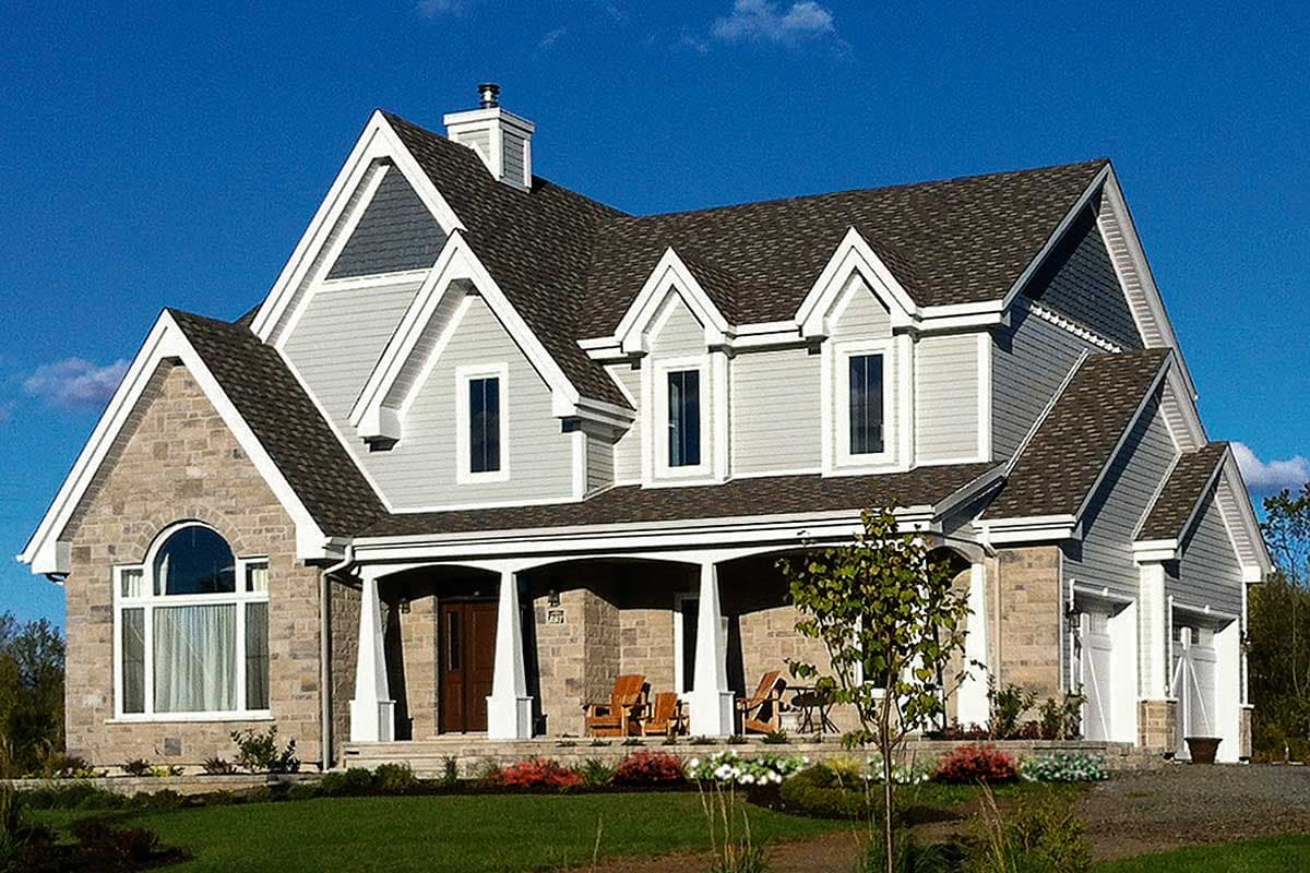House plan exterior: Two-story home with stone and vinyl siding, prominent gables, arched window, and covered porch.