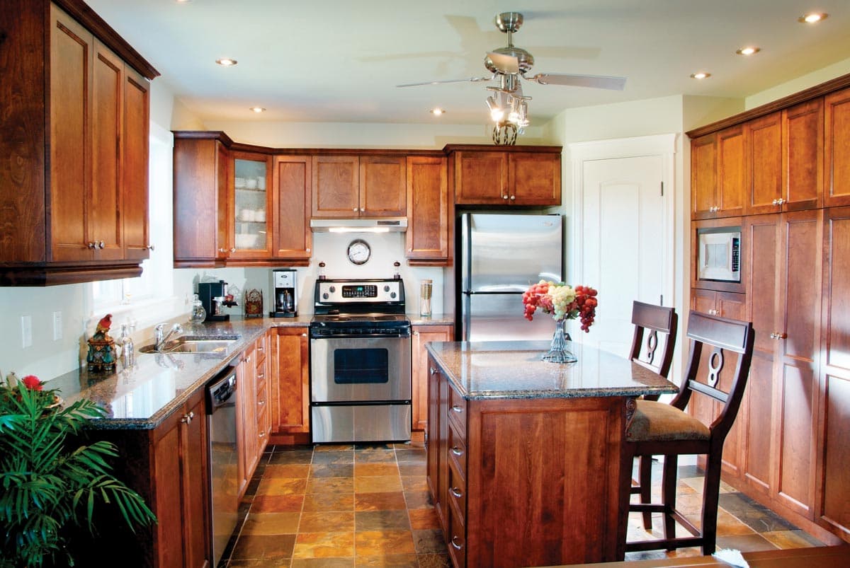 Kitchen with wood cabinetry, granite countertops, stainless steel appliances, and a central island with seating.