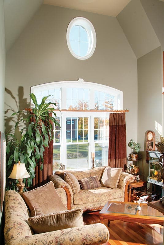 Interior view of great room with vaulted ceiling, arched window, and oval transom window.