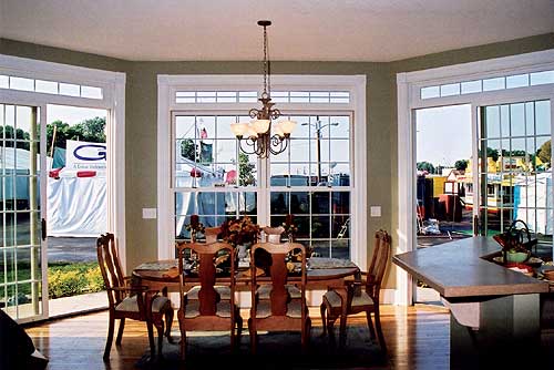 Dining area with large windows, French doors, and a partial view of a kitchen island.
