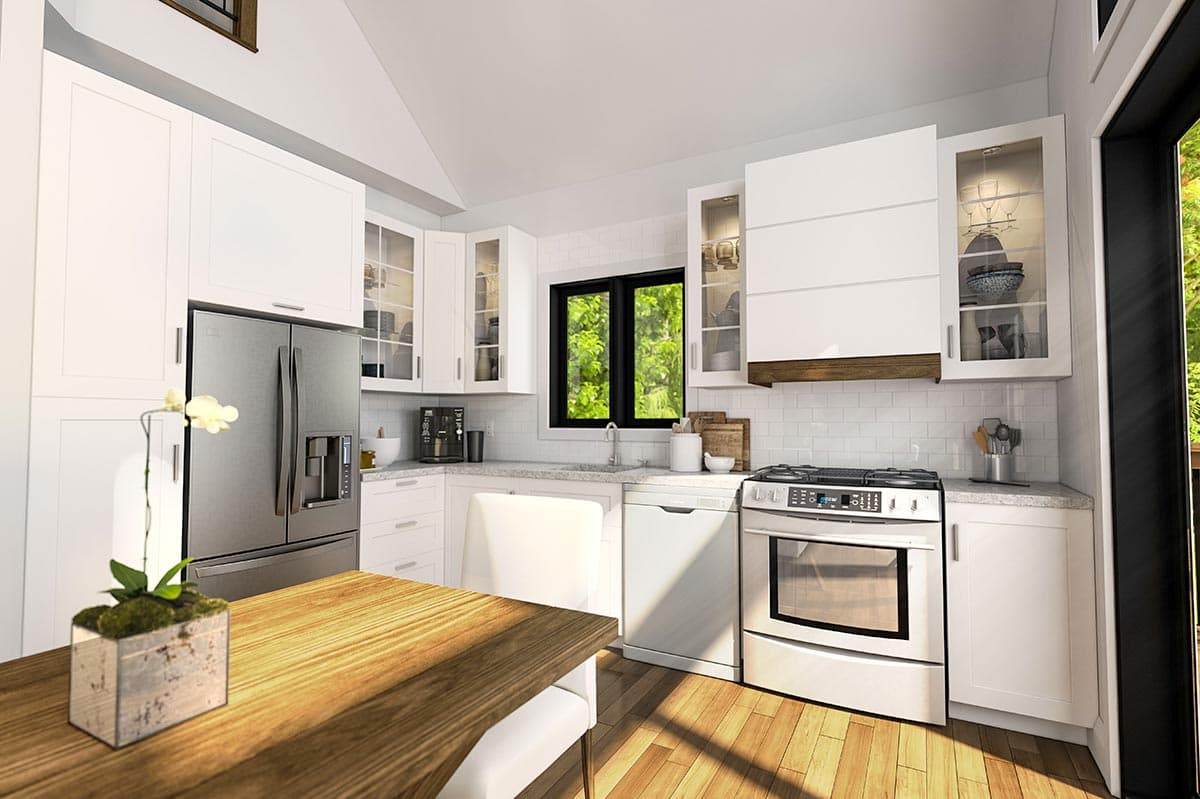 Modern kitchen with white cabinetry, stainless steel appliances, subway tile backsplash, vaulted ceiling, and a wooden dining table.