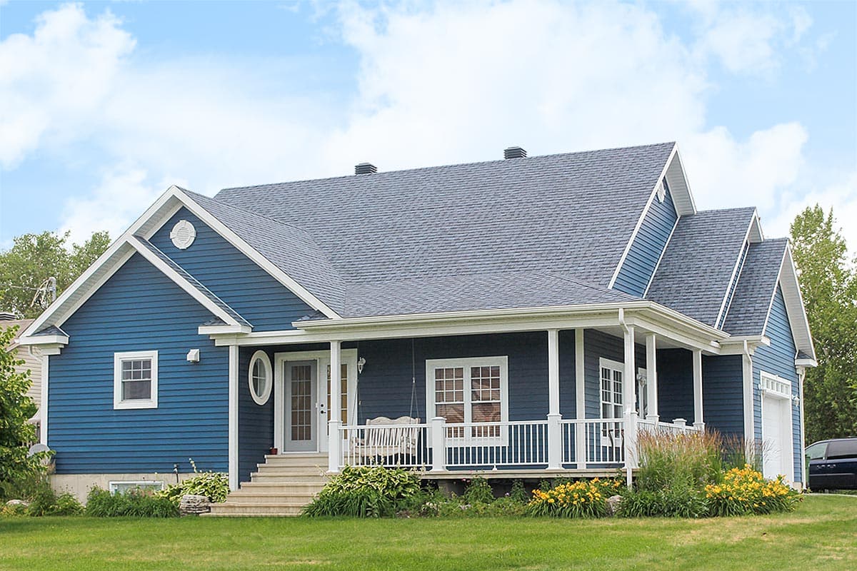 House plan exterior. Two-story, blue-sided home with a front porch, gables, and white trim. Features a side-entry garage.