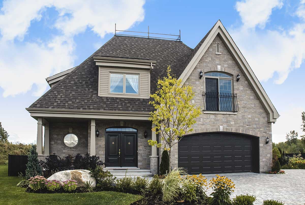 House plan exterior. Two-story home with a gabled roof, stone facade, and a two-car garage. Features include a front porch and dormer.