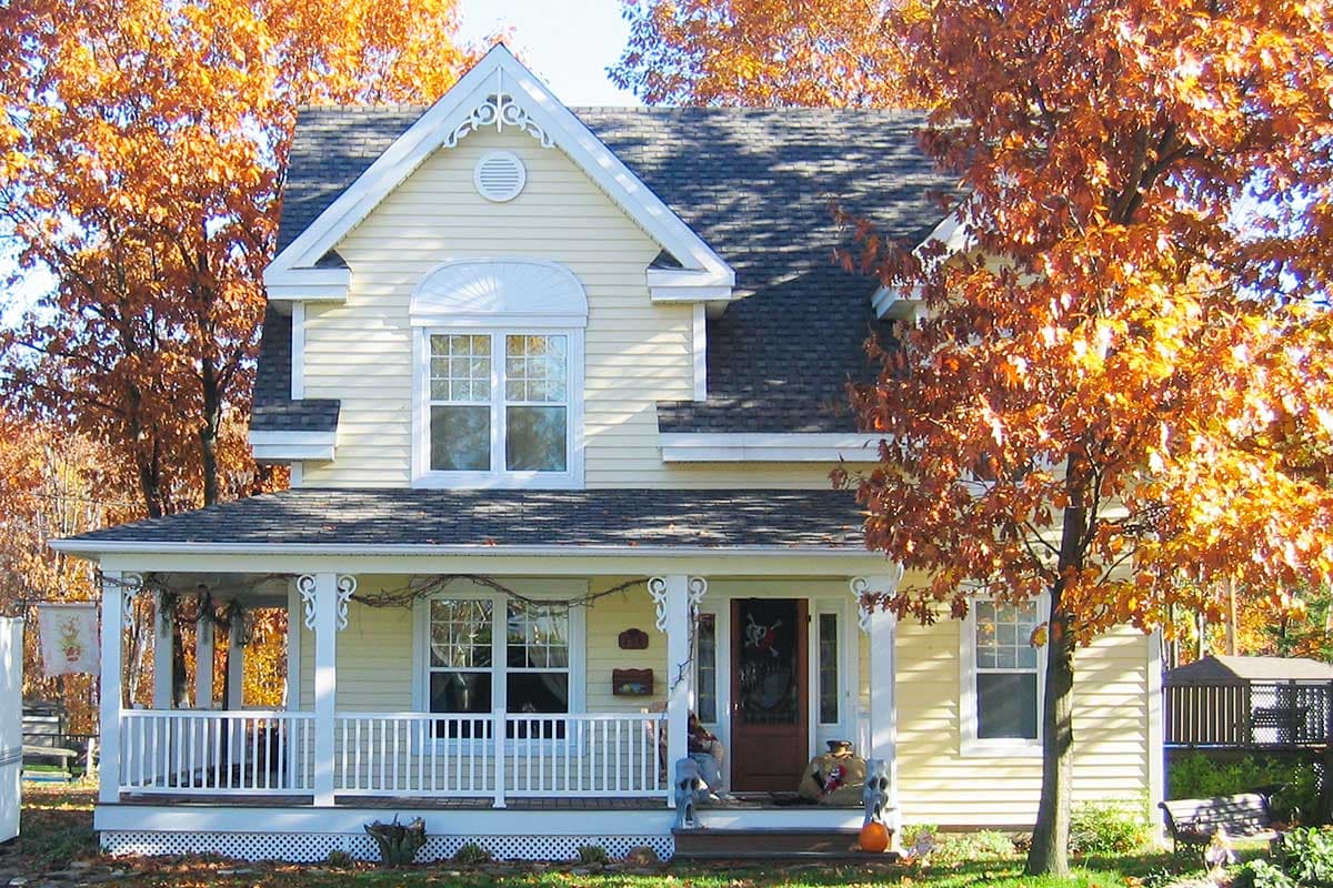 House plan exterior: Two-story cottage with wraparound porch, gabled dormers, and decorative gable trim.
