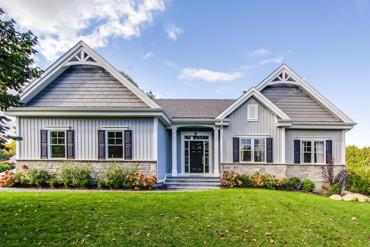 House plan exterior. Two-story home with Craftsman influence. Features include gabled rooflines, stone facade, and dark shutters on windows.