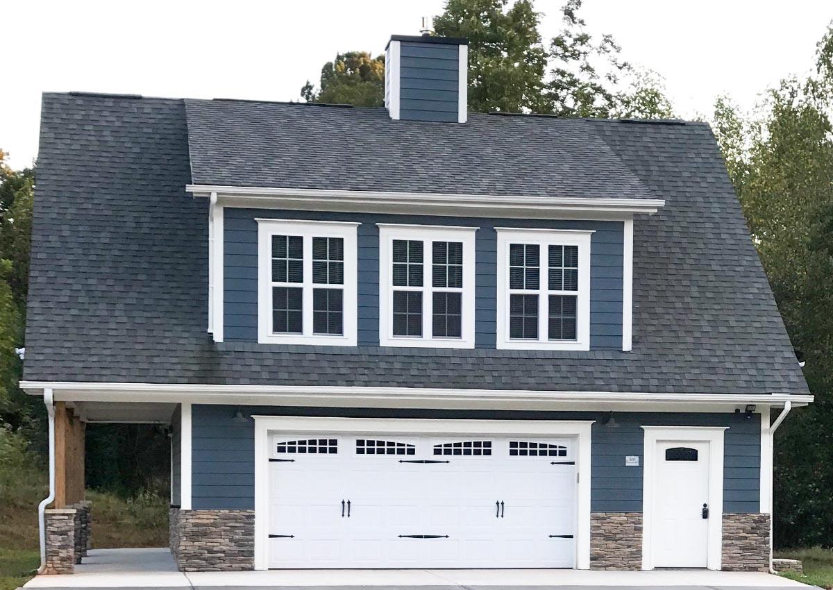House plan exterior featuring a two-car garage, stone accents, dormer windows, and covered carport.