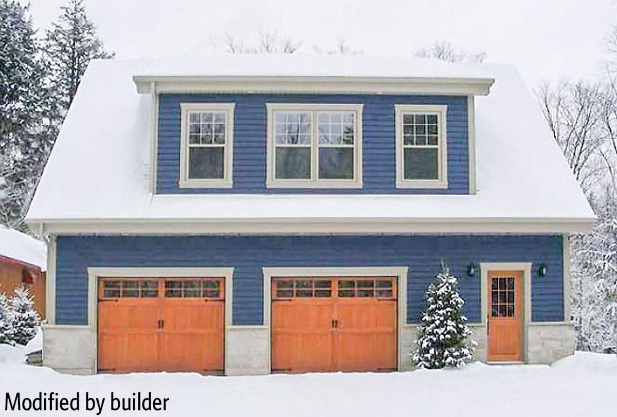 House plan exterior with blue siding, two wood garage doors, and a wood front door, covered in snow.