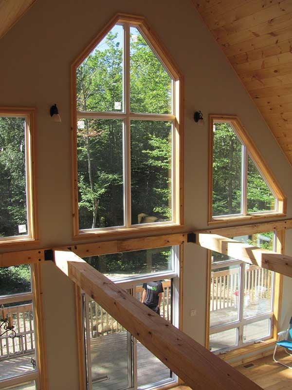 Interior view showcasing a vaulted ceiling with exposed wooden beams and large, multi-pane windows with angular framing.