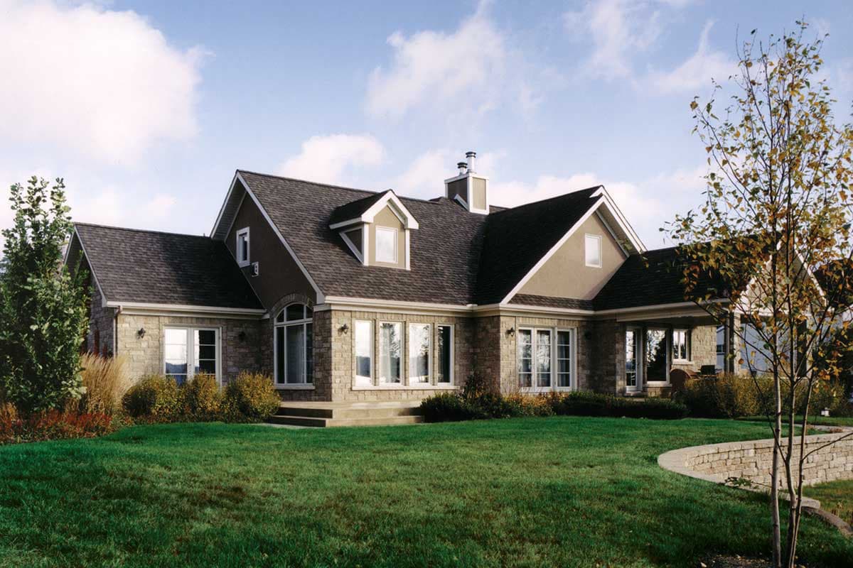 House plan exterior: Two-story home with stone facade, gabled dormers, arched entry, and covered porch.