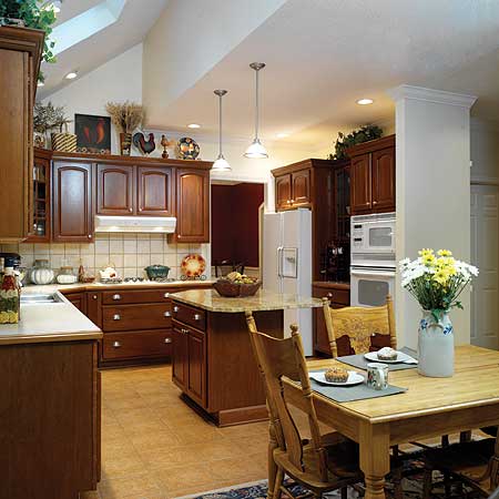 Kitchen with wood cabinetry, island, dining table, and vaulted ceiling with skylight.