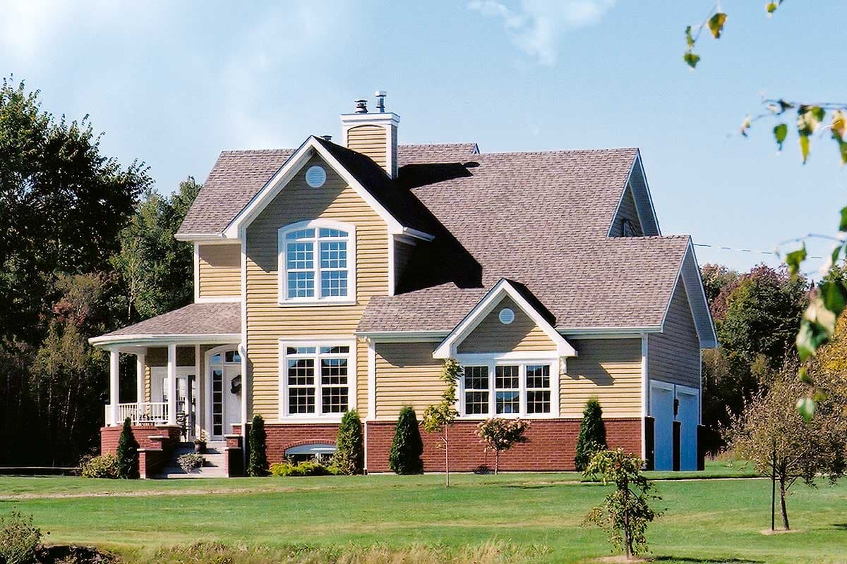 House plan exterior: Two-story, tan vinyl siding, gambrel roof, prominent gables, arched window, front porch, brick foundation.