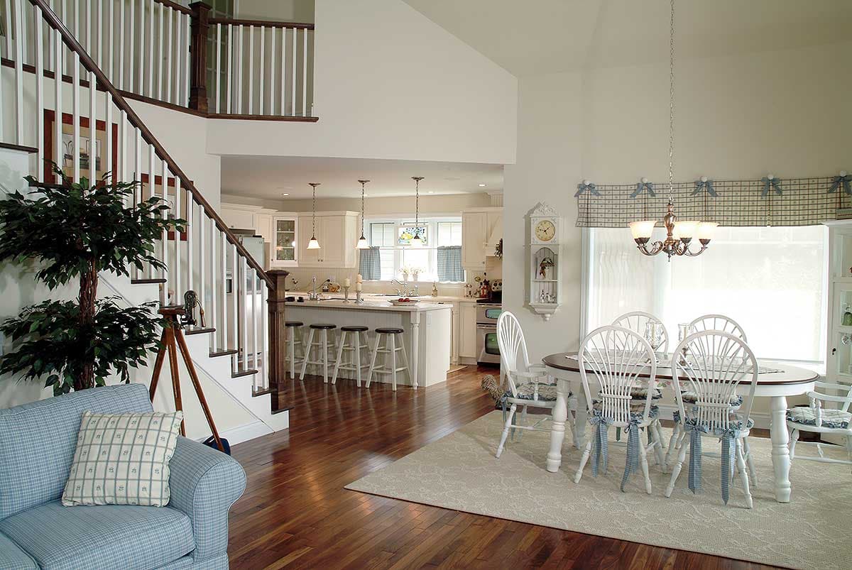 Open concept living area with a kitchen island, dining table, and staircase with white balusters.