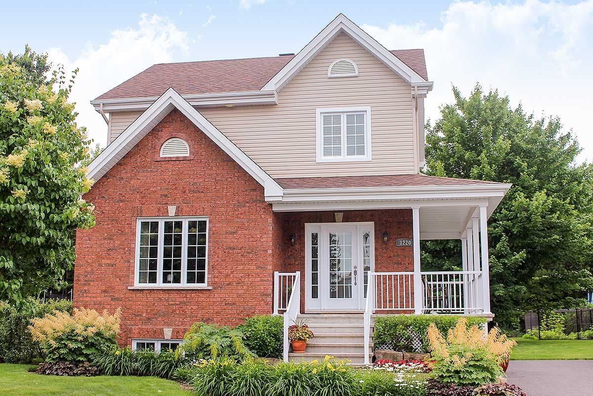 Two-story house plan exterior with brick lower level, vinyl siding upper level, prominent gables, covered porch, and white-trimmed windows.