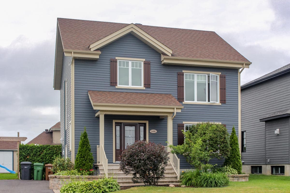 Two-story house plan exterior with a gabled roof, front porch, and decorative shutters on multiple windows.