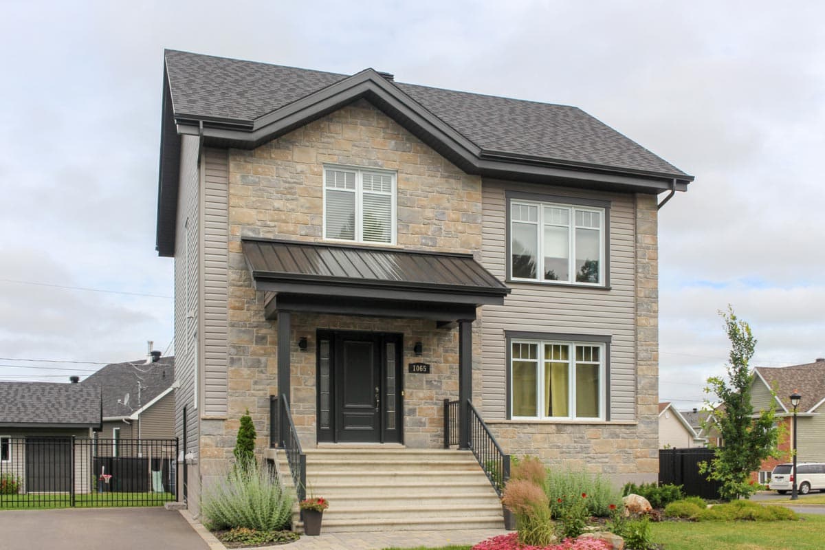 House plan exterior: two-story home with stone and vinyl siding, covered porch with metal roof, and multi-pane windows.
