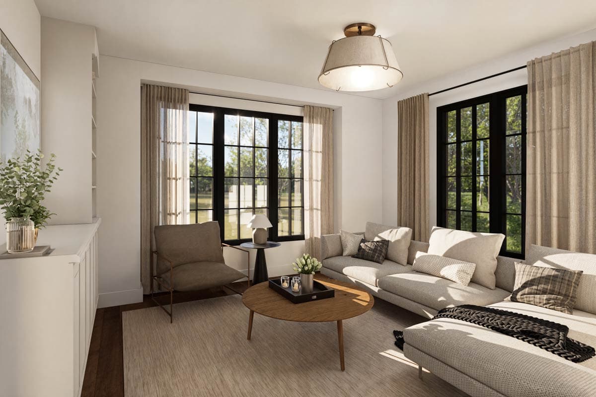 A modern living room featuring a sectional sofa, a round wooden coffee table, and large windows offering a view of greenery outside.