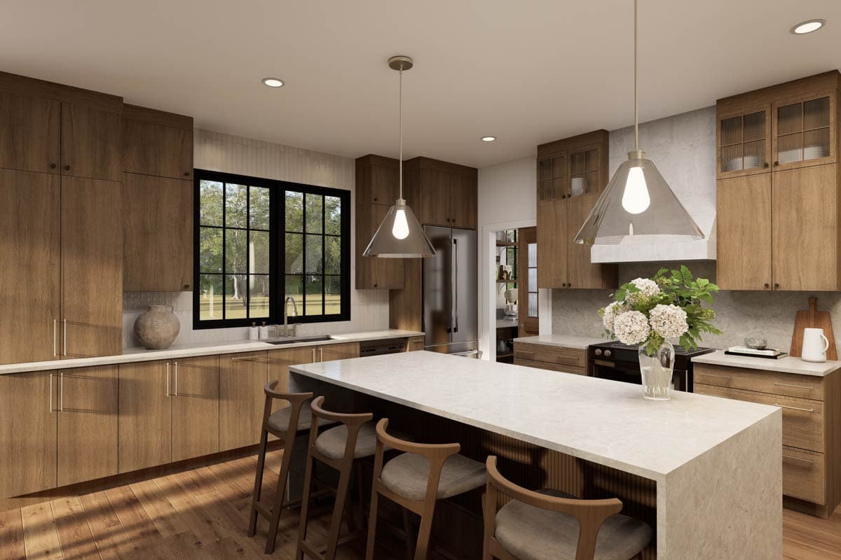 A modern kitchen features wooden cabinets and an island with bar stools. Large windows look out to a green, outdoor space. Pendant lights hang above.