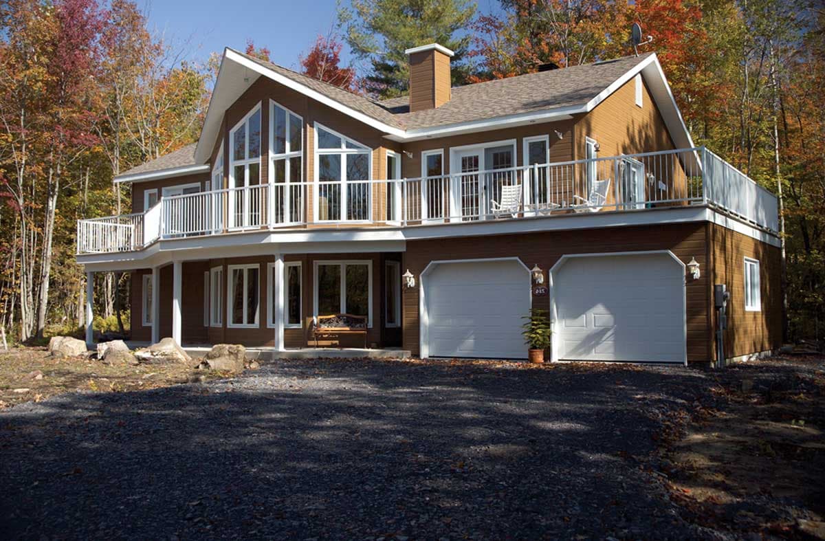 House plan exterior: Two-story modern home with a large second-story balcony, prominent gables, and a dual-car garage.
