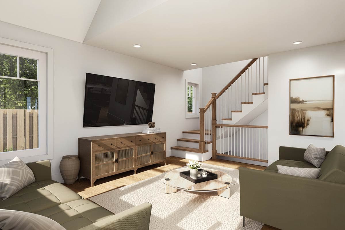 Living area with sectional sofa, wood console, large TV, glass coffee table, and staircase with white railings.