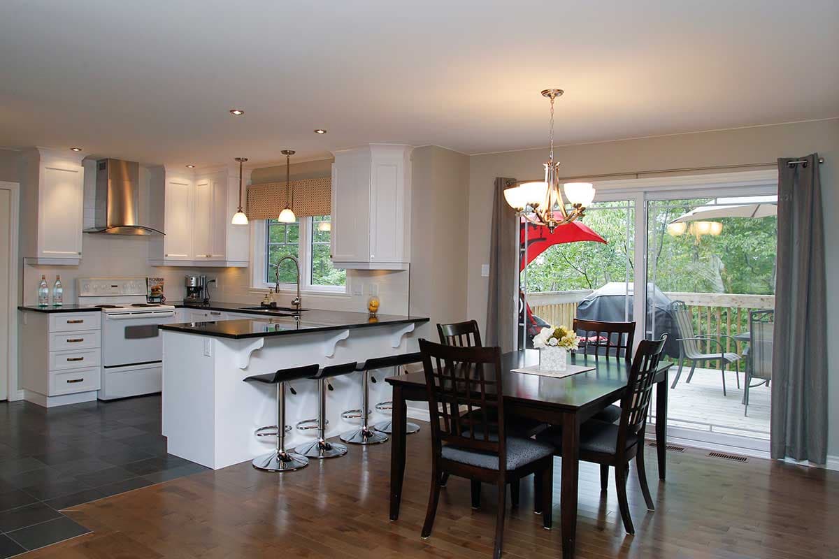 Open concept kitchen and dining area with an island, stainless steel appliances, and deck access.
