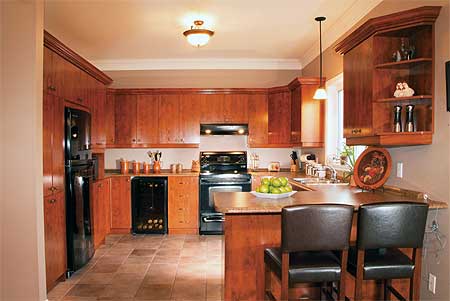 Kitchen interior with light wood cabinetry, granite countertops, a central island with bar seating, and stainless steel appliances.