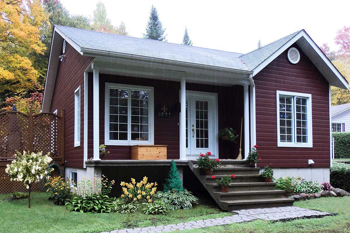 House plan exterior: One-story detached house with a covered front porch, symmetrical gabled roof, and double-entry doors.