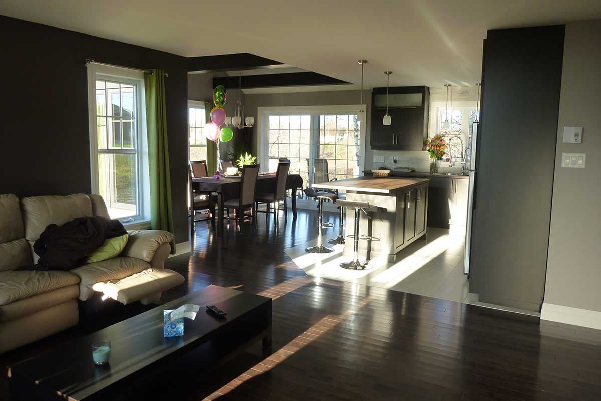 Open concept living area with dining table, kitchen island with seating, and large windows.