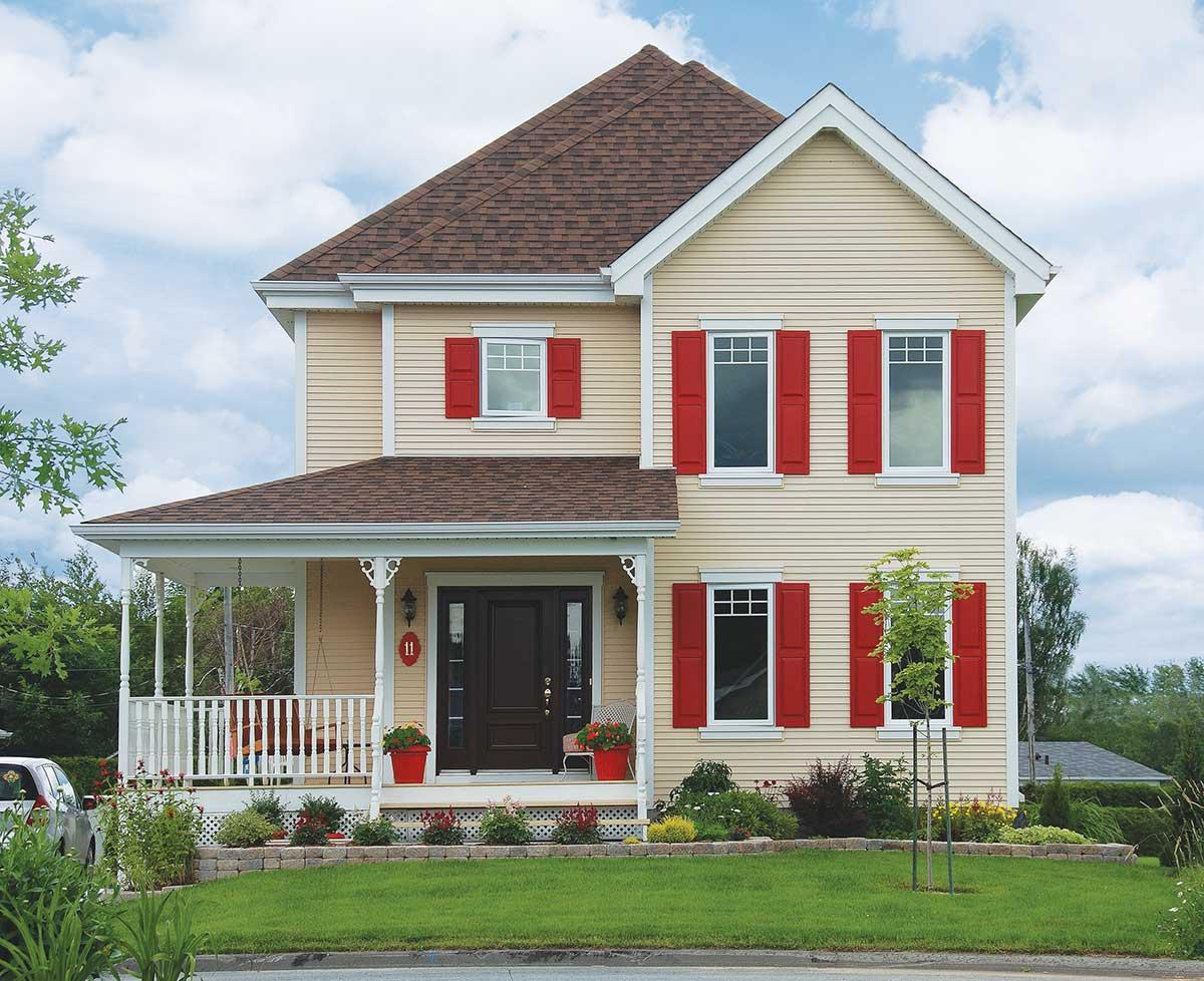 House plan exterior: Two-story home with wraparound porch, gable roof, and red shutters on windows.